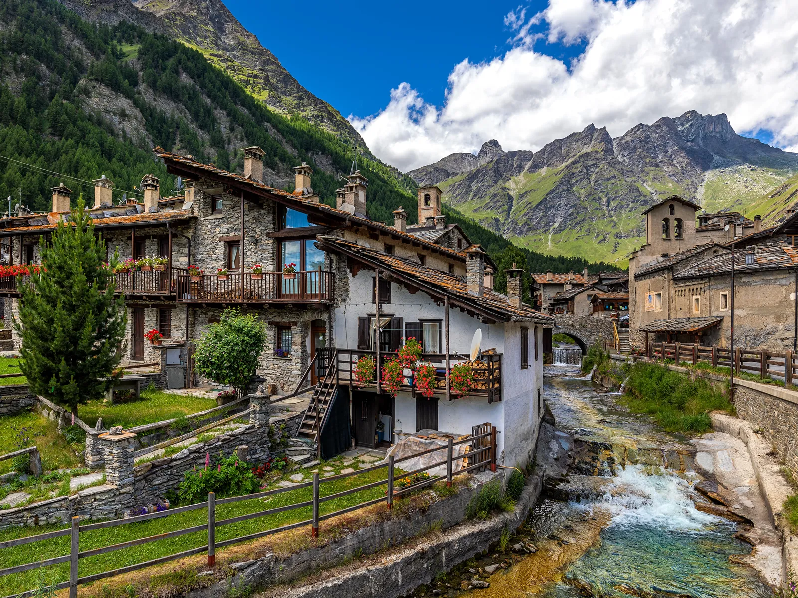 stone houses alpine river and mountains on background in chianale