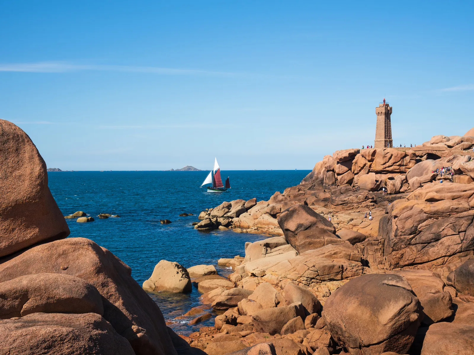 beautiful seaside landscape with sailing boat and ploumanach lighthouse at pink granite coast france brittany